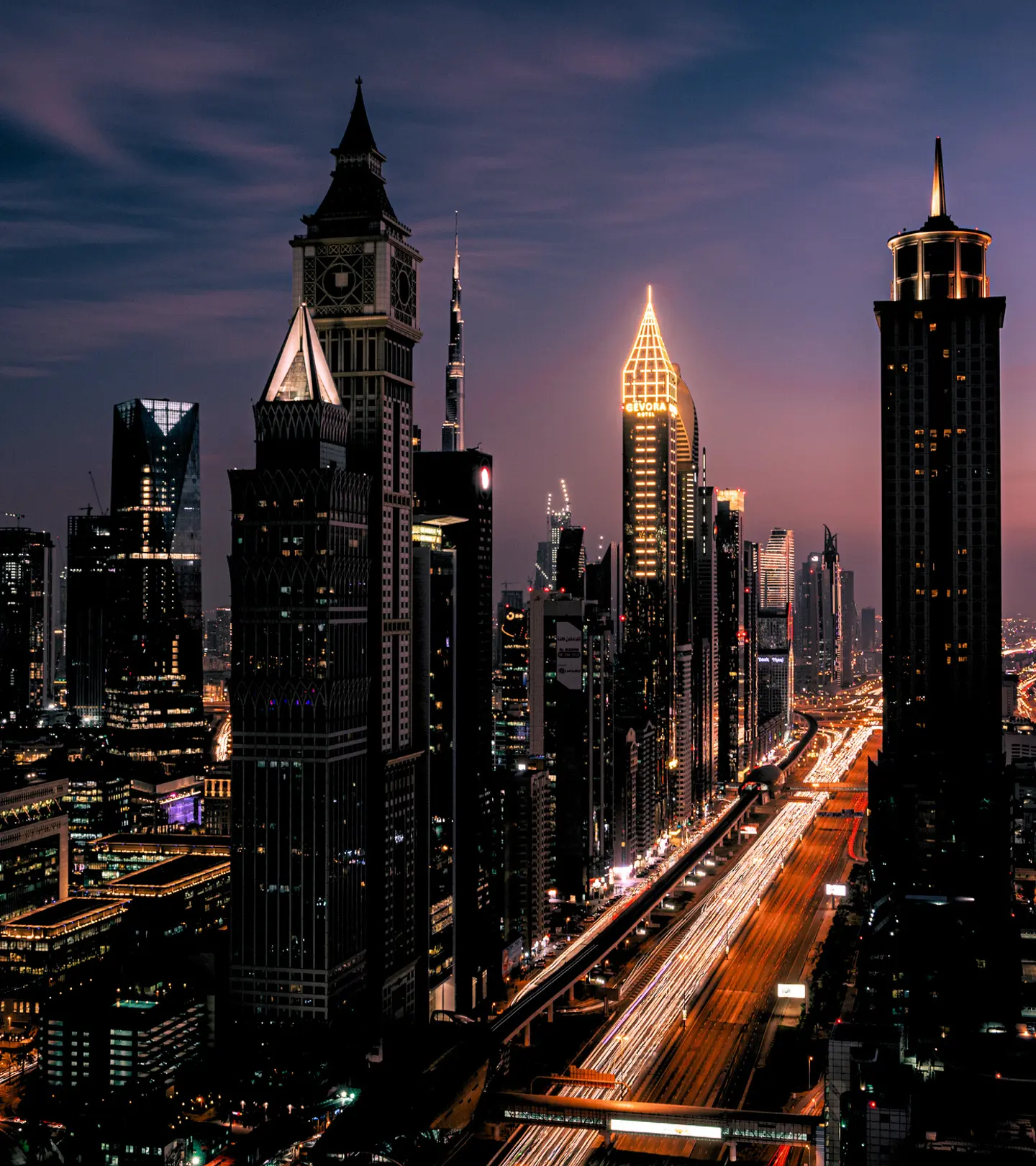 A vibrant night cityscape with illuminated skyscrapers and glowing highway light trails